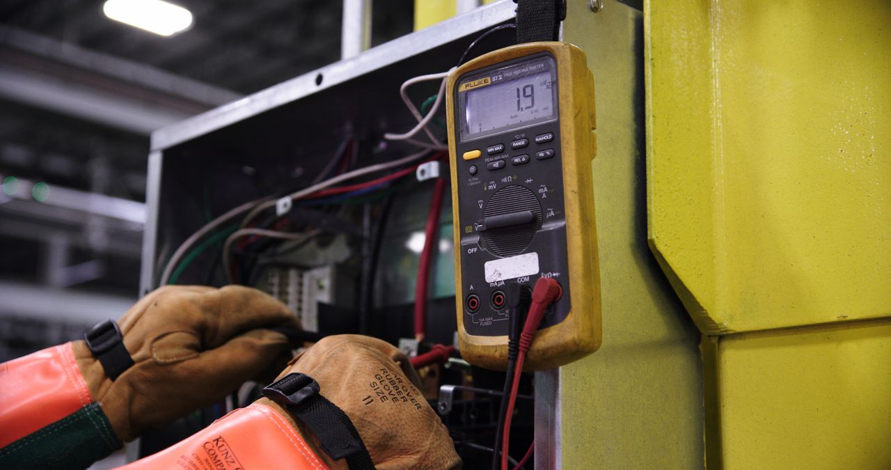 Crafting Captivating Headlines: Your awesome post title goes here Electrician using a multimeter to fix industrial control panel wiring.